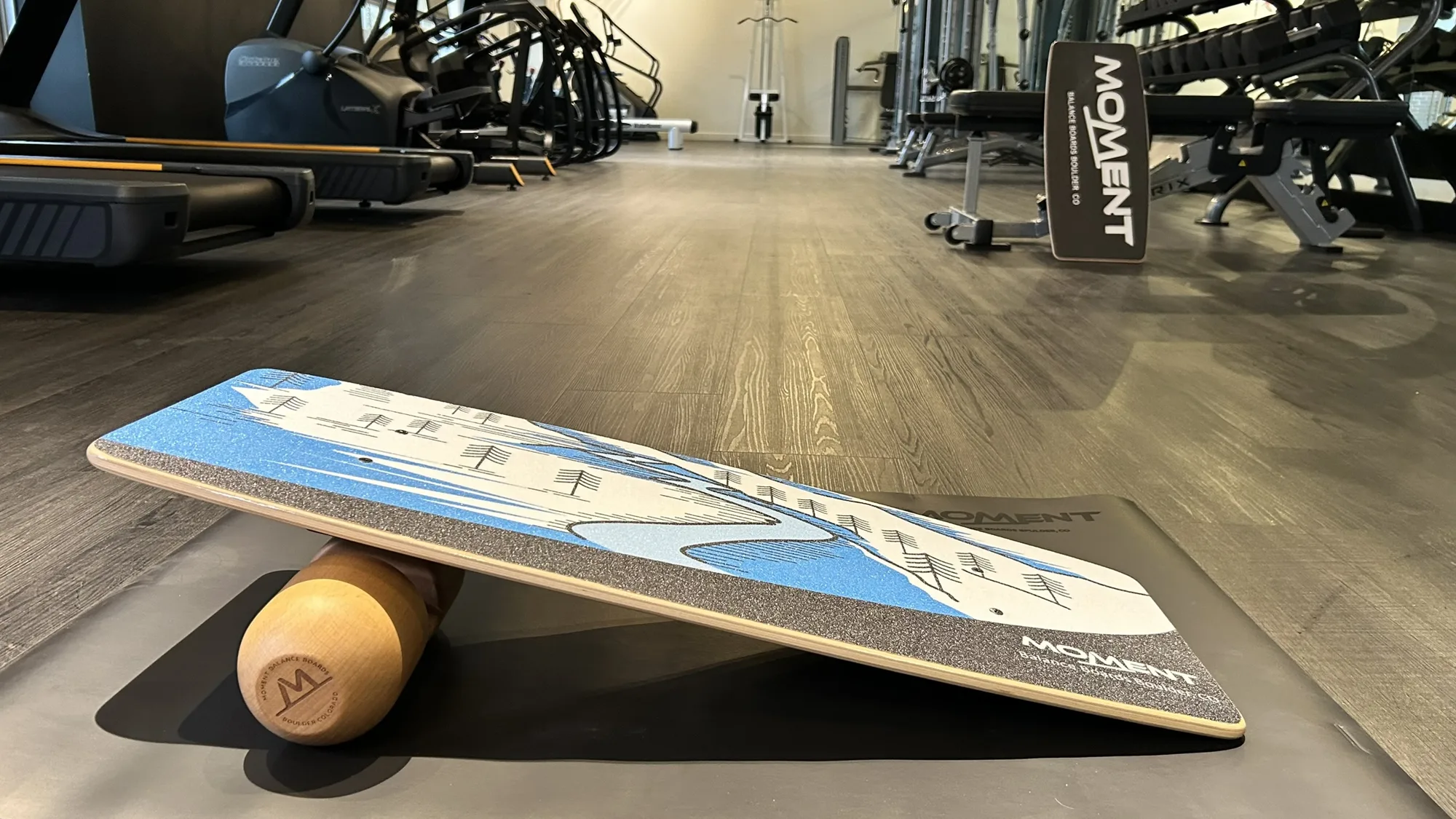 Moment Balance Board resting on its roller on a gym floor
