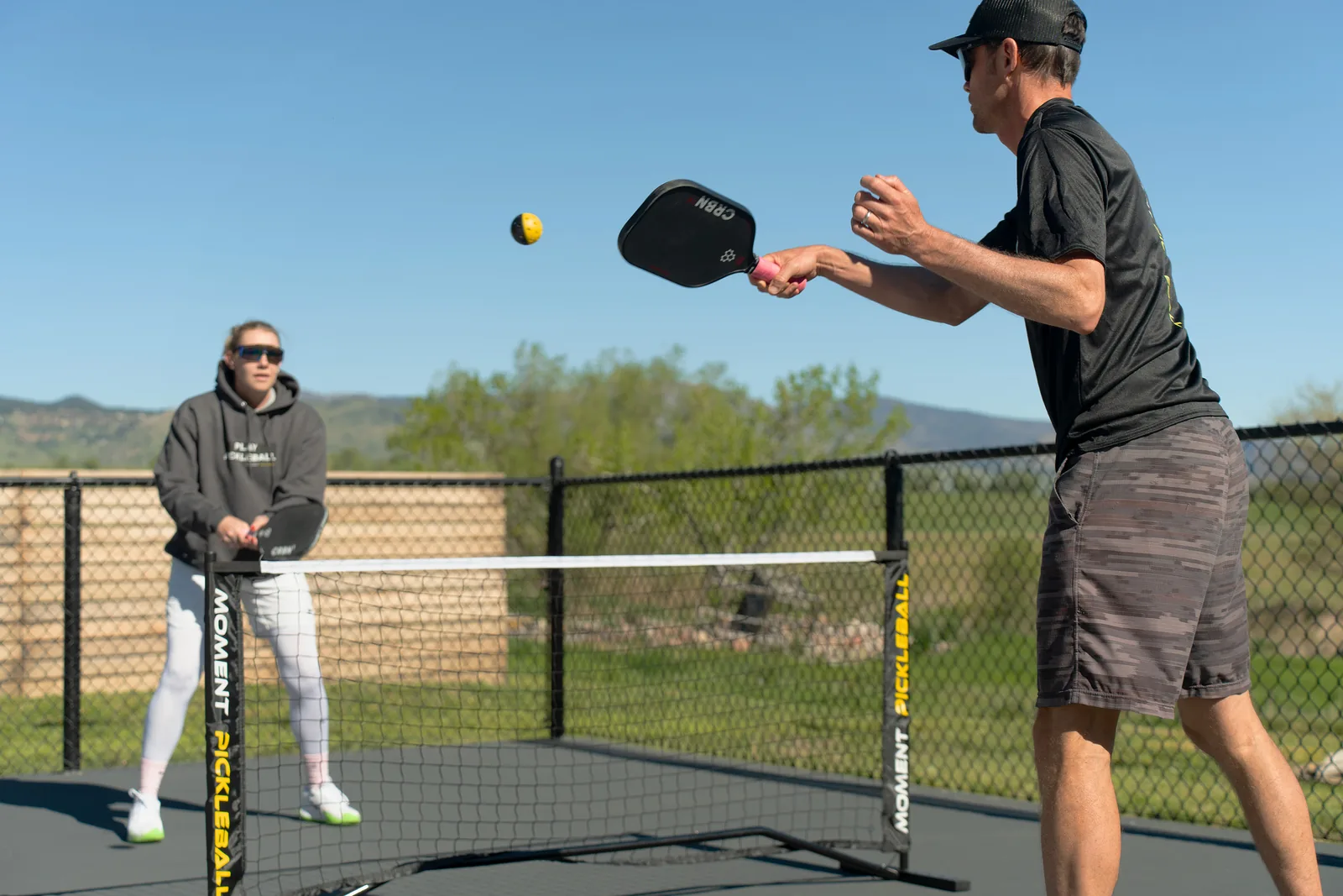 Two players rallying across a Moment net on an outdoor court