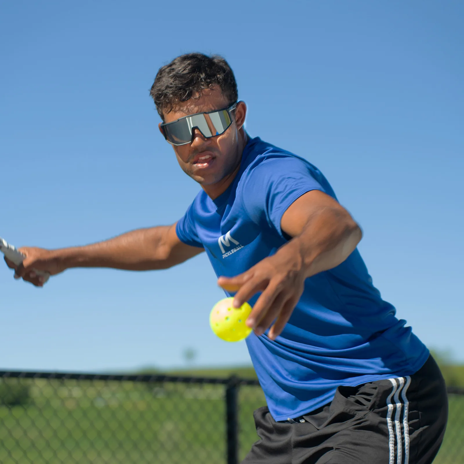 Player in a Moment shirt and Pro-Guard glasses reaching for a forehand
